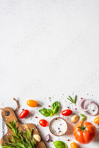 Food cooking background on white stone table. Fresh vegetables, herbs and spices with wooden cutting board. Ingredients for cooking with space for text, vertical image. photo