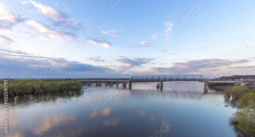 Evening landscape  sunset on the river. View of the industrial area of the railway bridge. Outskirts.