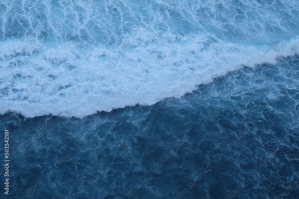 Obraz premium Beautiful scenic view of ocean with powerful waves in Bali island, Indonesia. Blue water background