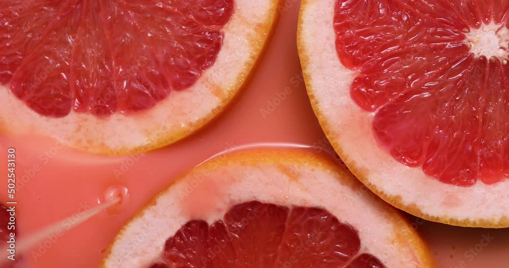 Top view rotation of fresh slice of grapefruits juice and gel serum , organic cosmetics, vitamin C, fresh citrus fruits, grapefruit extract Top view rotation of fresh slice of grapefruits juice and gel serum , organic cosmetics, vitamin C, fresh citrus fruits, grapefruit extract