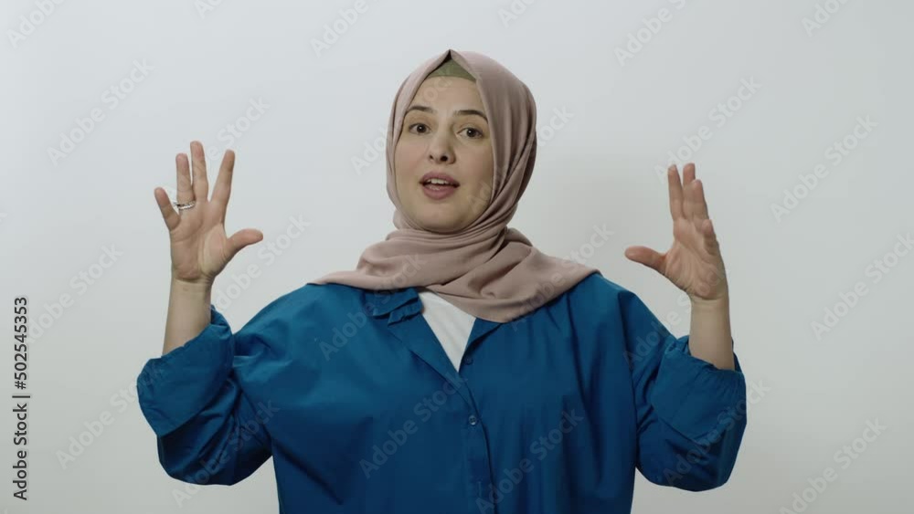 The hijab woman is very angry at what happened.Indoor studio shot isolated on white background. The woman is making fun of the interlocutor by making gestures or something.
