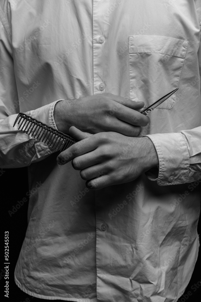  Barber holds a comb and scissors in his hands.