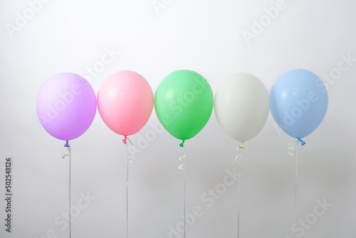 multicolored helium balloons in row on white background  festive mood  copy space