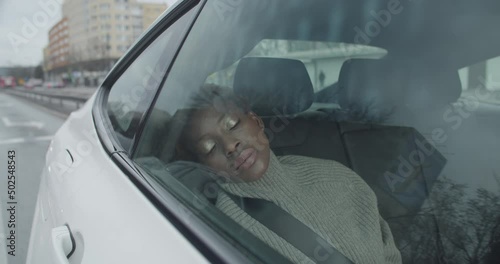Young Black woman taxi passenger trying to get some sleep on the backseat