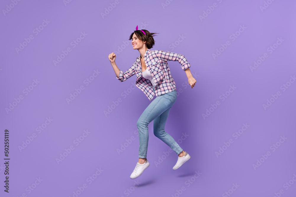 Photo of charming hurrying lady dressed checkered shirt jumping high running fast isolated purple color background