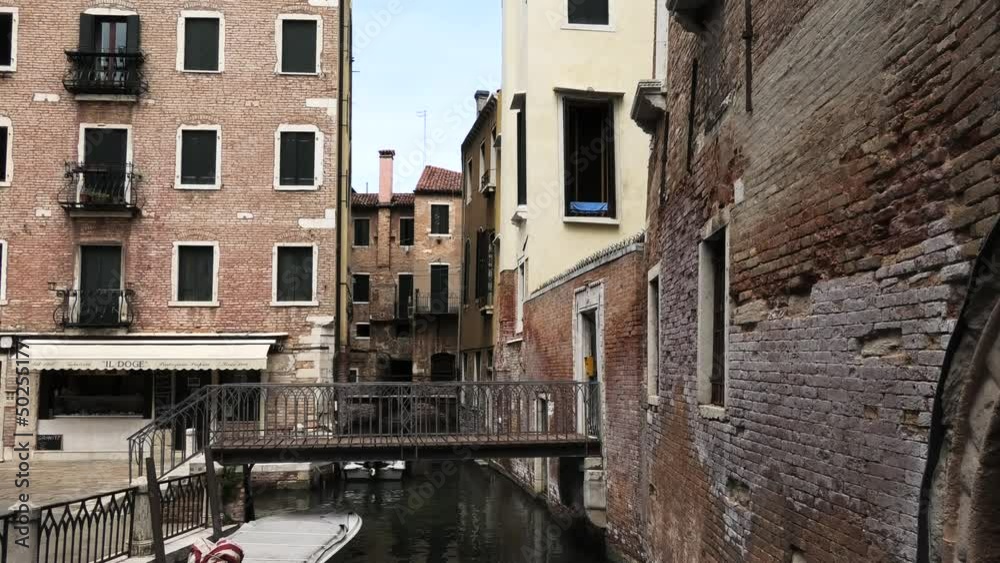 Quiet canal with small bridge in Venice, Italy with yellow and red houses Quiet canal with small bridge in Venice, Italy with yellow and red houses