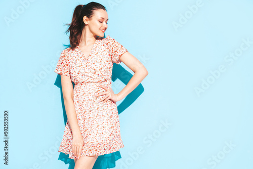 Portrait of young beautiful smiling female in trendy summer dress. Sexy carefree woman posing near blue wall in studio. Positive model having fun and going crazy. Cheerful and happy