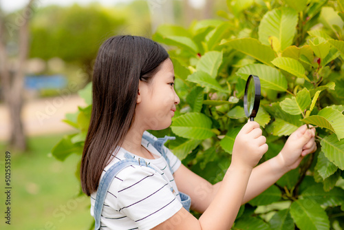 A girl using a magnifying glass to explore a tree. Learning outside the classroom.