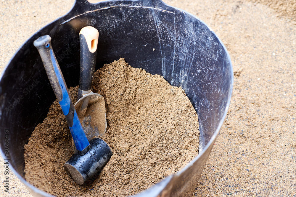 Tools for laying tiles are in a large bucket of sand. Instruments in the colors of the flag of Ukraine. Tools for laying tiles are in a large bucket of sand. Instruments in the colors of the flag of Ukraine.