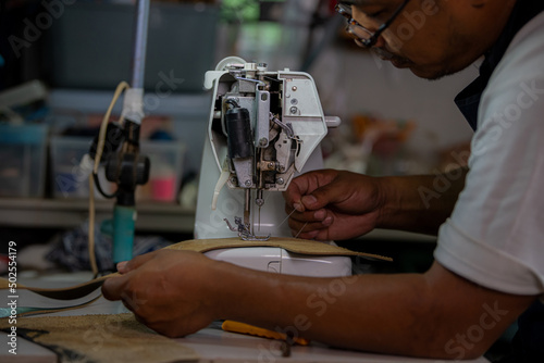 Working process of leather craftsman. Tanner or skinner sews leather on a special sewing machine, close up.worker sewing on the sewing machine