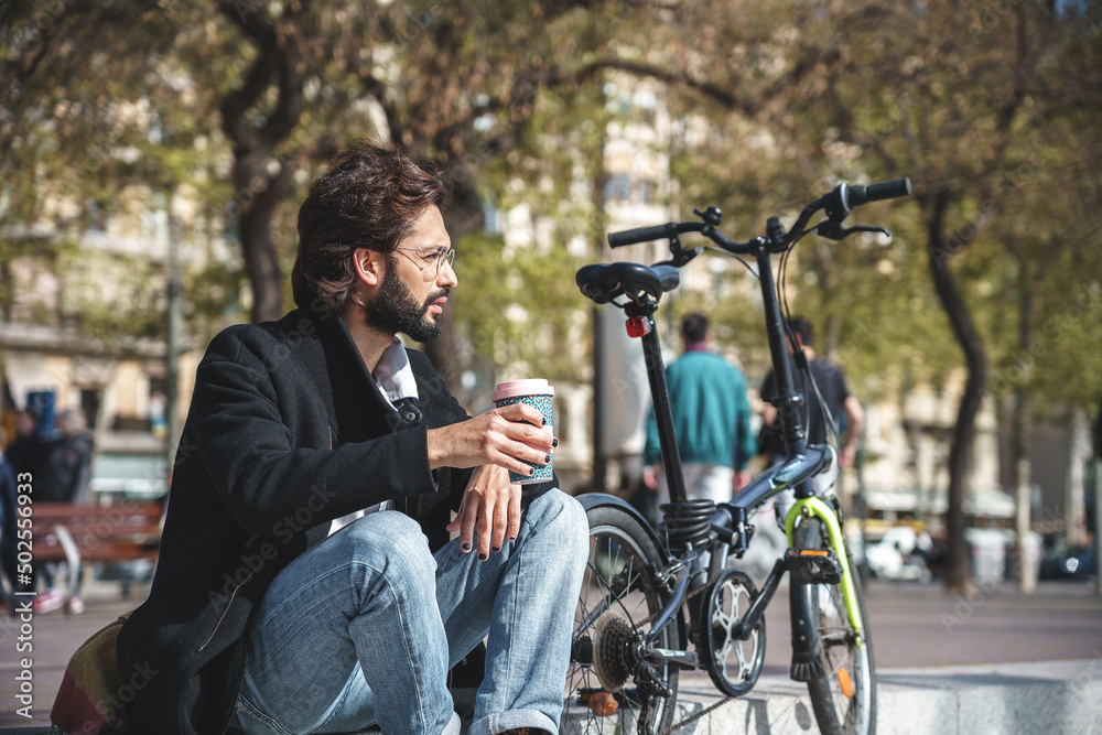  businessman drinks coffe while he is sitting whit his bicycle 