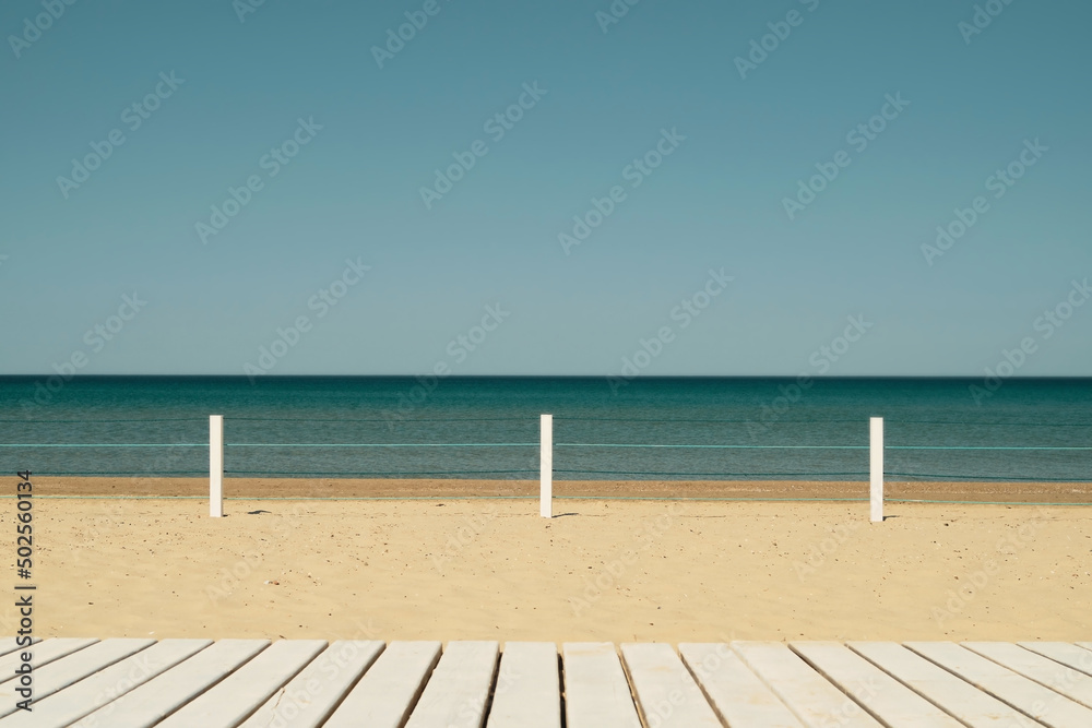 Wooden deck on a sandy beach in a resort town, light airy feel, blue cloudless sky. The idea of a beach holiday at sea, an idea for a banner