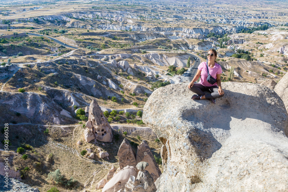 Woman meditate near ancient turkish fortress Uchisar Castle in Cappadocia. Anatolia, Turkey