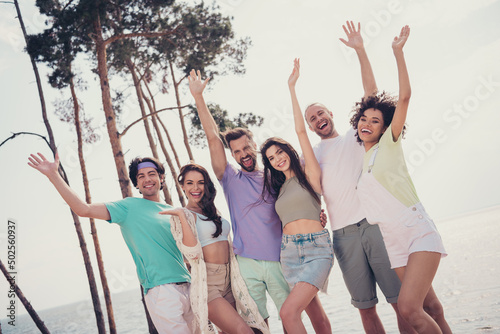 Photo of six people meeting embrace have fun raise hands enjoy vacation wear casual outfit nature seaside beach