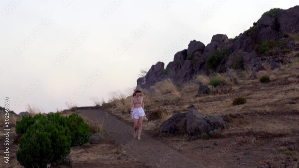 A young blond girl walks alone barefoot along a path on top of the mountain in the fog A young blond girl walks alone barefoot along a path on top of the mountain in the fog