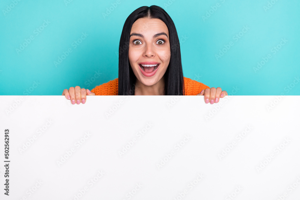 Photo of adorable impressed woman wear orange sweater holding big white empty space isolated turquoise color background Photo of adorable impressed woman wear orange sweater holding big white empty space isolated turquoise color background