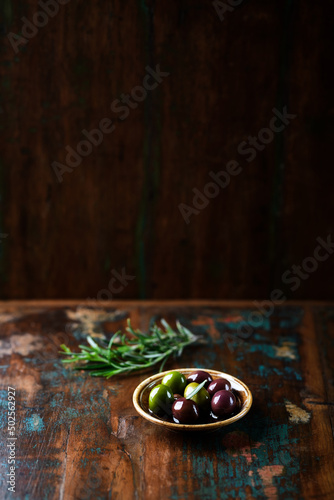 Various olives on rustic wooden background. Copy space. 