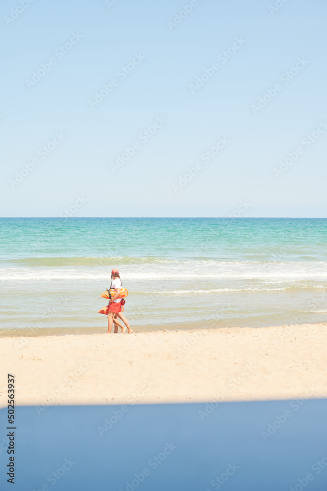 Two lifeguards walk along the shore of a Mediterranean beach checking that there are no accidents with bathers. safety on the shore Two lifeguards walk along the shore of a Mediterranean beach checking that there are no accidents with bathers. safety on the shore