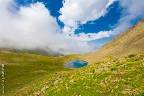 A lake in mountains, natural landscape, green meadows, snowy mountains, blue sky, winter season. Hakkari Cilo Sat Lakes photo