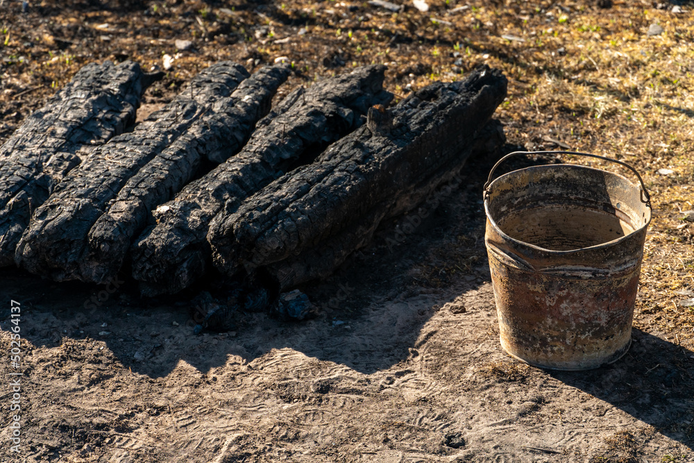 A wooden house in the village burned down because of a forest fire. Charred boards and various things lie on the ground, covered with ash and smoke. A wooden house in the village burned down because of a forest fire. Charred boards and various things lie on the ground, covered with ash and smoke.