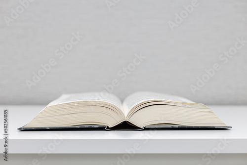 a thick book in an open form lies on a white table