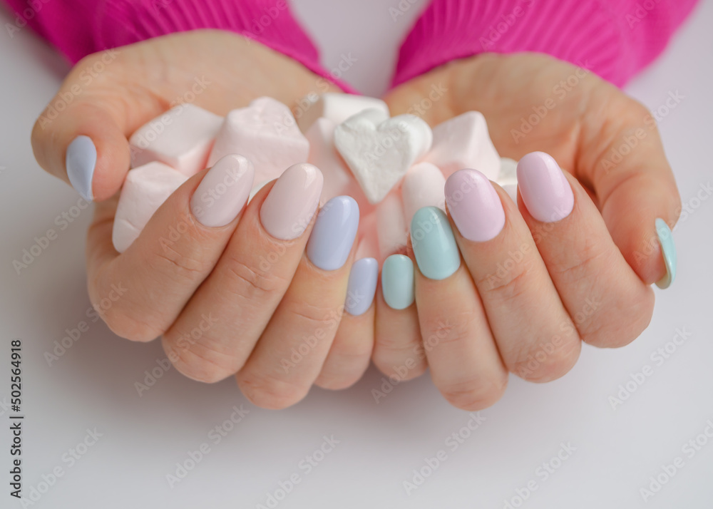 Beautiful female hands with delicate manicure and marshmallows. Spring and summer coating gel polish Beautiful female hands with delicate manicure and marshmallows. Spring and summer coating gel polish