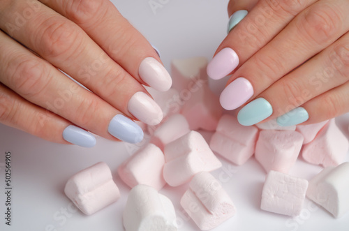 Beautiful female hands with delicate manicure and marshmallows. Spring and summer coating gel polish