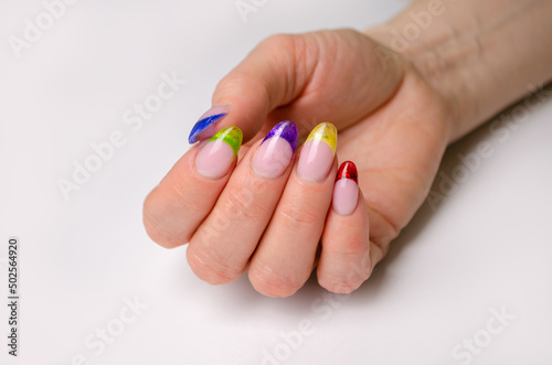 A beautiful female hand with a French manicure. Extended nails with stained glass gel of different colors