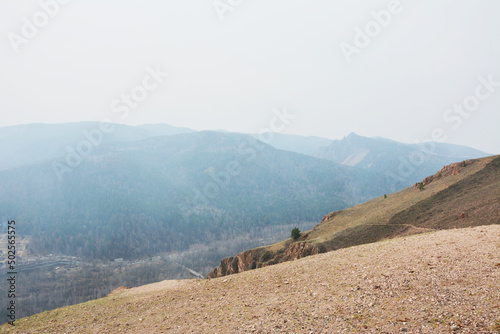 Landscape mountain slopes overgrown with forest in the haze of forest fires