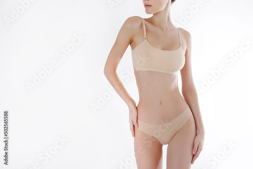 Close up shot of unrecognizable fit woman in lingerie isolated on white background. Torso of slim attractive female with flat belly in white underwear. Copy space for text.