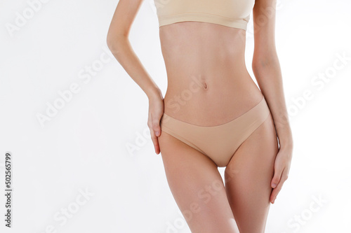 Close up shot of unrecognizable fit woman in lingerie isolated on white background. Torso of slim attractive female with flat belly in white underwear. Copy space for text.