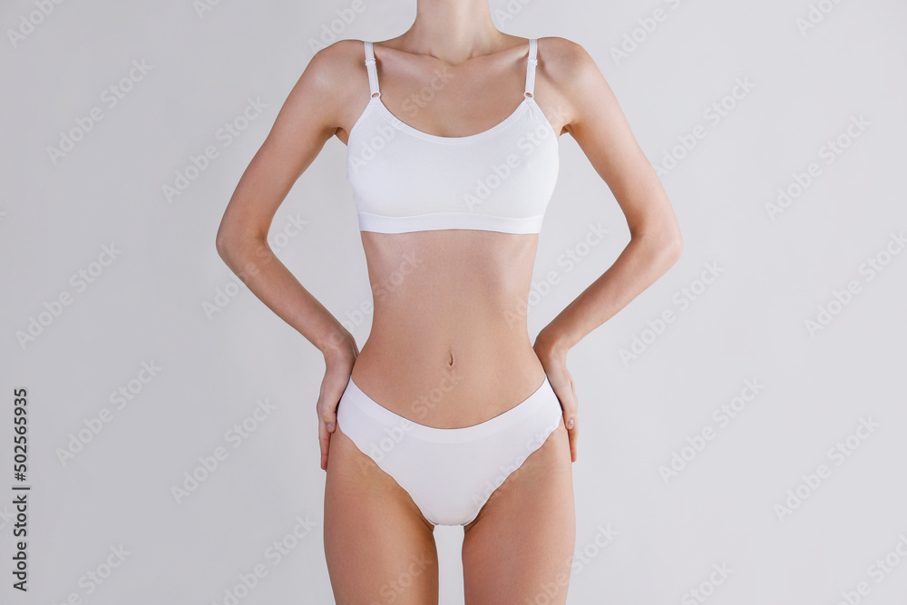 Close up shot of unrecognizable fit woman in lingerie isolated on white background. Torso of slim attractive female with flat belly and thin waist in white underwear. Copy space for text.