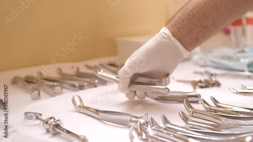 Dentist hand picks up tool from set of dentist tools for surgery photo