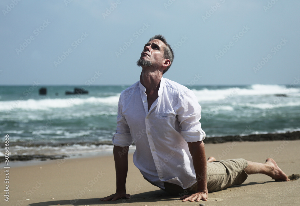 Yoga lesson. A man practices yoga near the sea.