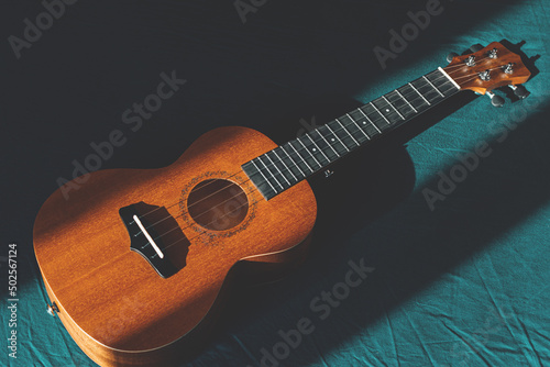 Top view ukulele body, soundhole, bridge and neck on green textile.
