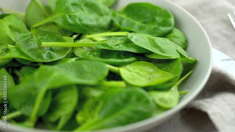 Bowl with fresh green spinach, a grilled salmon steak and female pressing lime juice on it, close-up Bowl with fresh green spinach, a grilled salmon steak and female pressing lime juice on it, close-up