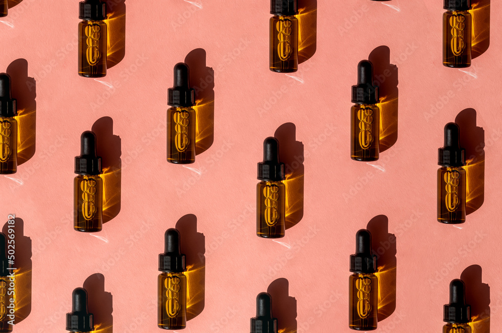 Pattern of Transparent amber green glass dropper bottles with liquid inside on pink beige background in the sunlight. Pipette with fluid hyaluronic acid, serum, retinol. Cosmetics, healthcare, beauty Pattern of Transparent amber green glass dropper bottles with liquid inside on pink beige background in the sunlight. Pipette with fluid hyaluronic acid, serum, retinol. Cosmetics, healthcare, beauty