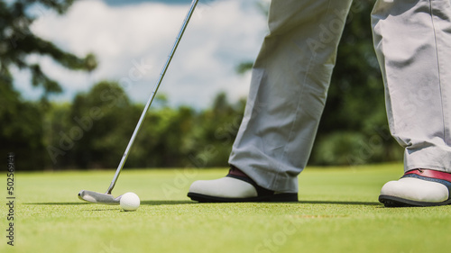 The golfer places the golf ball on the golf green into the hole.