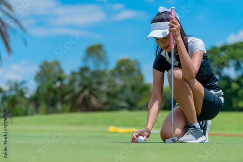 The golfer places the golf ball on the golf green into the hole.