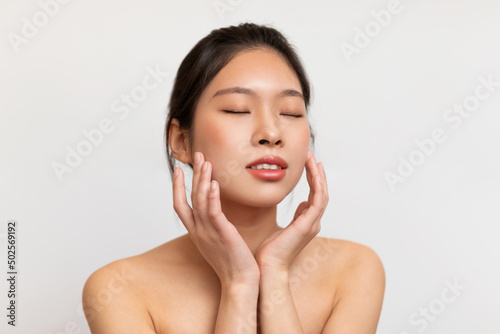 Beauty portrait of young Asian woman touching her clean face