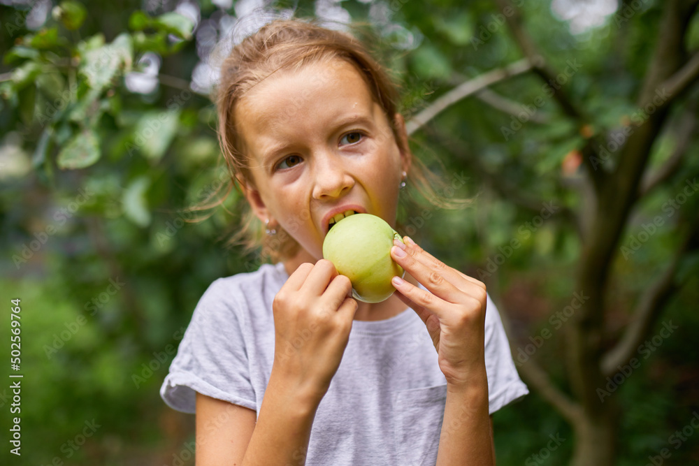 Cute little girl eat green apple in home garden outdoor, happy child Cute little girl eat green apple in home garden outdoor, happy child