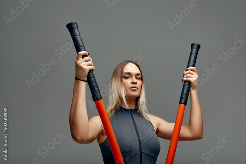 beautiful girl in sports uniform is training kung fu in the studio, fighter athlete, practicing martial arts with a stick