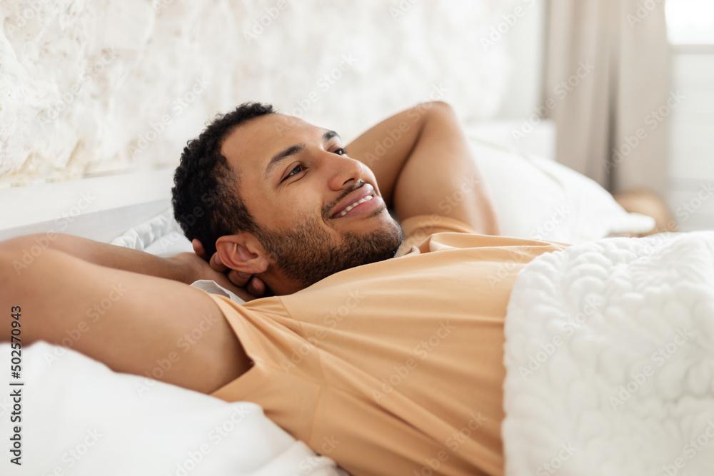 Happy Middle Eastern Man Relaxing Lying Resting In Cozy Bedroom
