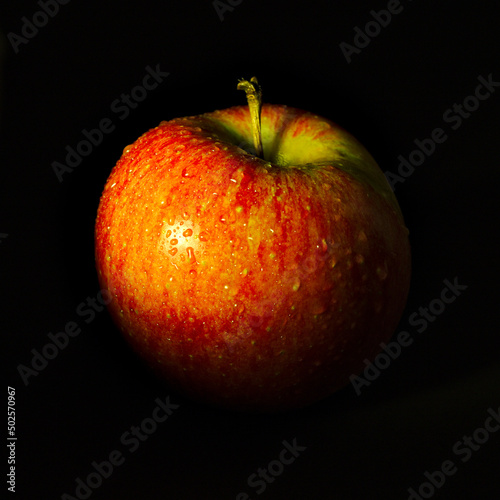 Świeże dojrzałe czerwone jabłko na czarnym tle. Low key.