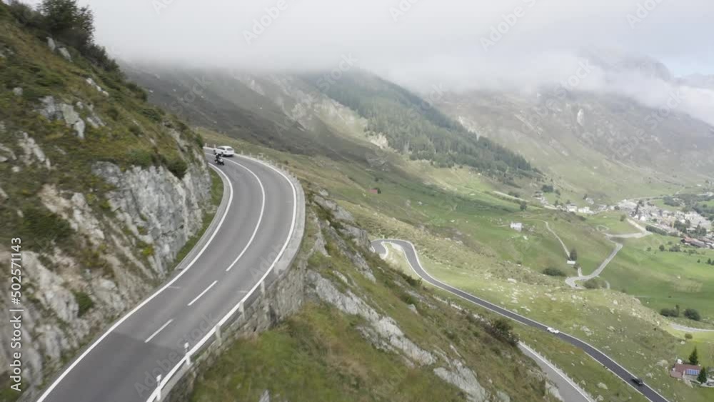 Car driving down a road on the side of a green and lush mountain with tons of fog in the background Car driving down a road on the side of a green and lush mountain with tons of fog in the background