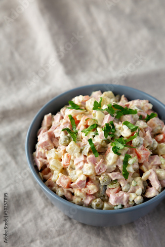 Homemade Olivier salad in a Bowl on a white wooden background, side view. Copy space.
