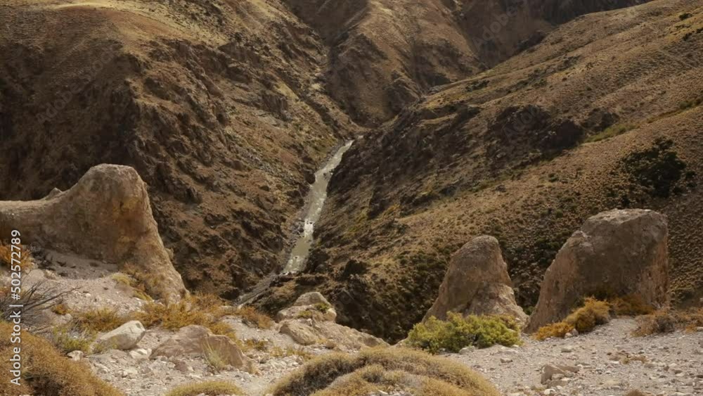 Arid environment high in the mountains. View of the rocky cliffs and river flowing across the Andes cordillera. Arid environment high in the mountains. View of the rocky cliffs and river flowing across the Andes cordillera.