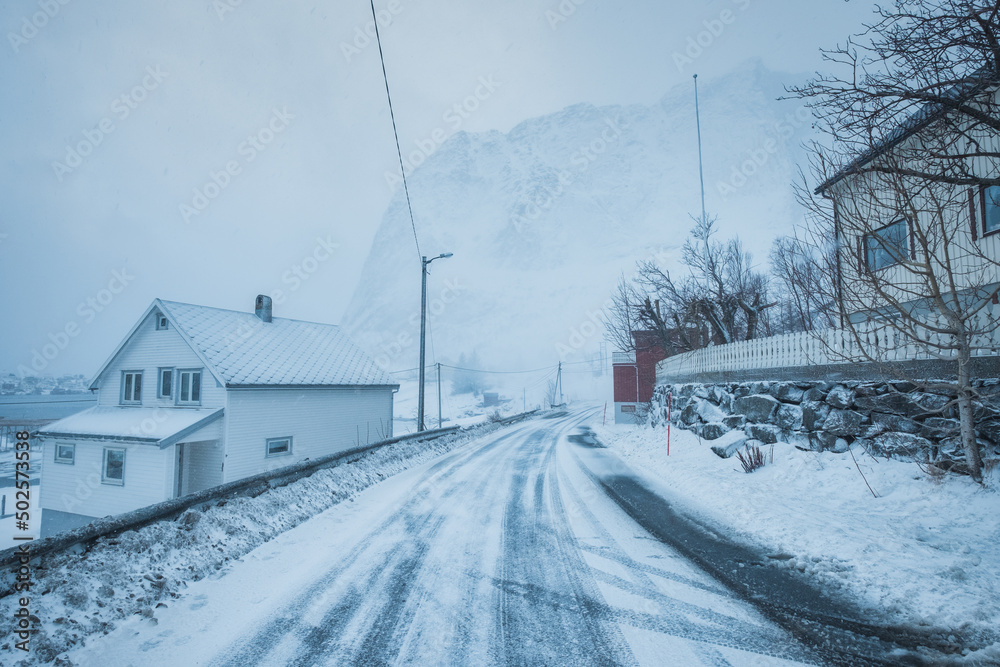 Fishing village with snow mountain on the road in snow storm on winter at Lofoten Islands