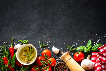 Food background. Fresh vegetables, spices and herbs at black stone table. Top view with space for design.
