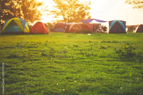 Selective focused on Lawn or green grass ground of camping ground near the sea beach. with camping tent in the background.
